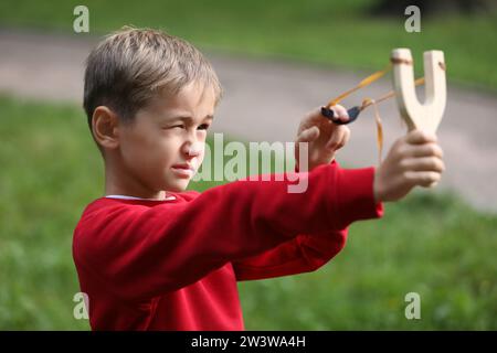 Petit garçon jouant avec la fronde dans le parc Banque D'Images