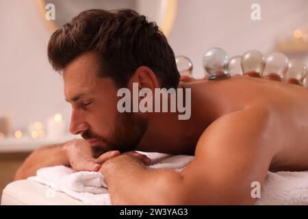 La thérapie par ventouse. Homme avec des tasses en verre sur le canapé de massage dans le salon de spa Banque D'Images