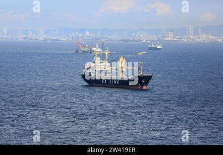 Navire cargo général sud-coréen Sky Glory, compagnie maritime coréenne CK Line, dans la région de la baie d'Osaka, Japon, pont Yumemai et horizon de la ville d'Osaka en arrière-plan Banque D'Images