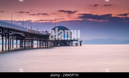 La longue jetée dans les Mumbles, Swansea, au sud du pays de Galles. La structure en bois et en acier se trouve dans une mer calme, avec un ciel rouge derrière elle, au lever du soleil Banque D'Images