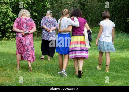 Cinq femmes de différentes générations marchent sur la pelouse de jardin vue arrière Banque D'Images