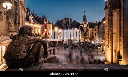 Sarlat-le-Canéda, France - 19 septembre 2023 : 'le Badaud' ou Onlooker, une sculpture en bronze de Gérard Auliac, surplombe les acheteurs de Noël au crépuscule Banque D'Images