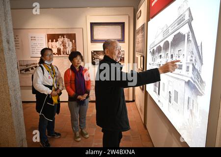 JINJIANG, 21 décembre 2023 (Xinhua) -- le villageois local Cai Wenshi (à droite) parle du processus de construction d'un bâtiment historique avec des touristes dans le village de Wulin de Jinjiang, dans la province du Fujian, dans le sud-est de la Chine, le 19 décembre 2023. Dans le village de Wulin, dans la province du Fujian de l'est de la Chine, les visiteurs sont souvent fascinés par le mélange de styles architecturaux : maisons locales en briques rouges, bâtiments gothiques, structures gréco-romanes et bâtiments mêlant éléments chinois et occidentaux. Le mélange éclectique de styles architecturaux raconte de façon vivante l'histoire de la connexion du village avec l'outre-mer Banque D'Images