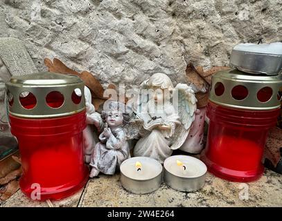 Lanternes et figurines d'ange sur une pierre tombale dans le cimetière public Banque D'Images