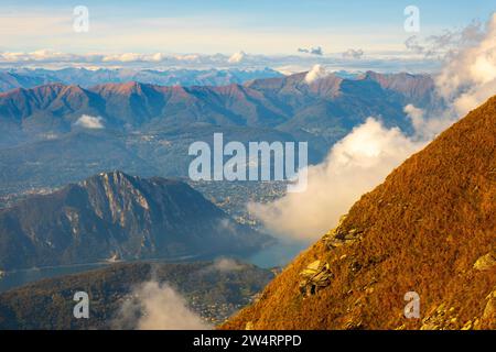 Vue aérienne sur le magnifique paysage montagneux avec des nuages et le lac de Lugano et la ville de Lugano dans une journée ensoleillée au Tessin, Suisse, Europe Banque D'Images