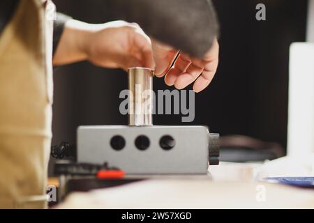 Luthier fabricant de luth méconnaissable artisan à deux mains exécutant le processus de bandes de ronflage de contrôleur de courbure dans l'outil de fer pour un nouveau dos et avant brut Banque D'Images