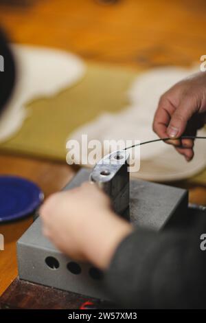 Méconnaissable luthier artisan fabricant de luth mains dans son atelier exécutant le processus de ronflage de contrôleur de courbure dans l'outil de fer pour un nouveau dos et avant brut Banque D'Images