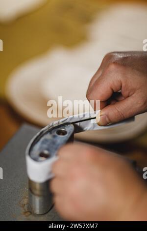 Luthier fabricant de luth méconnaissable artisan à deux mains exécutant le processus de bandes de ronflage de contrôleur de courbure dans l'outil de fer pour un nouveau dos et avant brut Banque D'Images