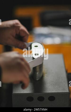 Luthier fabricant de luth méconnaissable artisan à deux mains exécutant le processus de bandes de ronflage de contrôleur de courbure dans l'outil de fer pour un nouveau dos et avant brut Banque D'Images