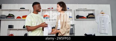 jeunes et joyeux entrepreneurs interraciaux discutant de démarrage dans le studio d'impression textile, bannière Banque D'Images