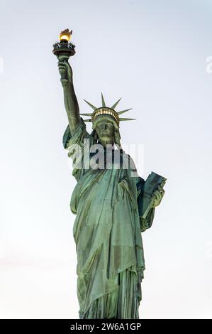 D'en bas de pierre vieillis célèbre Statue de la liberté située sur le piédestal dans la ville de New York contre un ciel terne sans nuages Banque D'Images