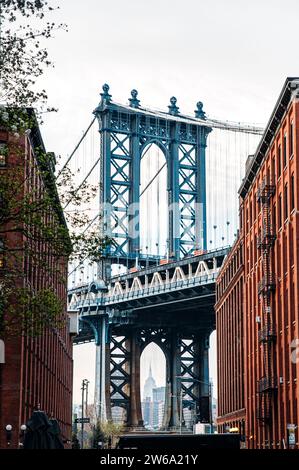 Une vue pittoresque sur le pont de Manhattan depuis une rue pavée de DUMBO, Brooklyn, avec des bâtiments historiques flanquant les deux côtés. Banque D'Images