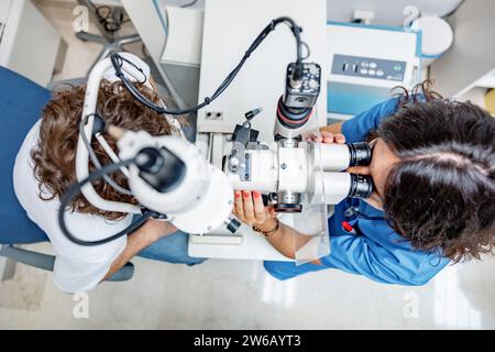 Vue latérale d'une jeune femme médecin anonyme en uniforme médical et avec stéthoscope regardant loin tout en étant assis avec un patient anonyme masculin à Split lam Banque D'Images