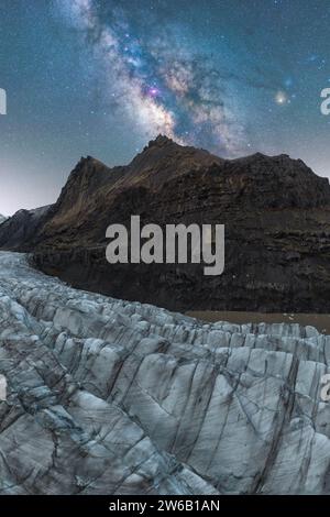 Une vue imprenable sur la voie lactée qui s'étend au-dessus de la surface accidentée du glacier Vatnajokull, capturée à la tombée de la nuit dans la vaste nature sauvage d'Islande. Banque D'Images