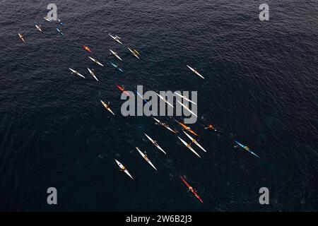 Une photo aérienne à couper le souffle capturant un groupe de kayakistes naviguant sur les eaux calmes de la mer dans une formation structurée, mettant en valeur un mélange d'humains Banque D'Images