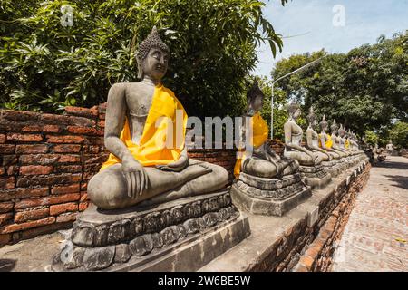 Statues antiques de Bouddha méditant avec tissu jaune enveloppé dans le temple oriental traditionnel Wat Yai Chai Mongkhon à Ayutthaya Thaïlande dans le jour ensoleillé Banque D'Images