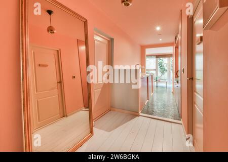Couloir mur rose avec sol et grand miroir en plus du comptoir de cuisine dans un appartement moderne Banque D'Images
