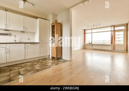 Spacieux salon vide relié à la cuisine de l'appartement moderne avec plancher de bois franc et fenêtres Banque D'Images