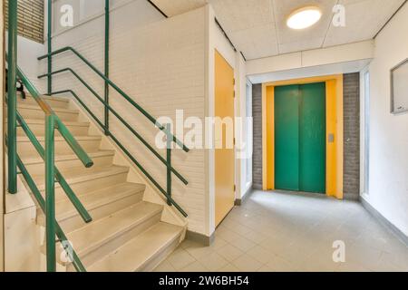 Intérieur de l'immeuble de bureaux moderne avec escalier vide et couloir menant à l'ascenseur vert et carrelage blanc Banque D'Images