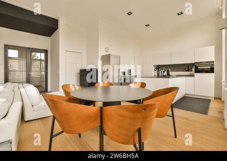 Table ronde en bois et chaises brunes dans la salle à manger contemporaine de la maison moderne avec cuisine en arrière-plan Banque D'Images