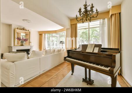 Piano avec grand canapé confortable dans un salon spacieux avec fenêtres lumineuses et lustre dans un appartement luxueux Banque D'Images