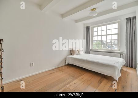 Cette chambre minimaliste lumineuse et aérée dispose d''un lit simple avec du linge blanc, de parquet et de grandes fenêtres avec des rideaux gris. Banque D'Images