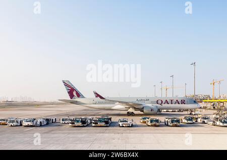 Vue latérale d'un avion Airbus A350-900 de Qatar Airways et d'un avion Douglas remorquant des tracteurs à l'aéroport international Hamad à Doha, Qatar Banque D'Images
