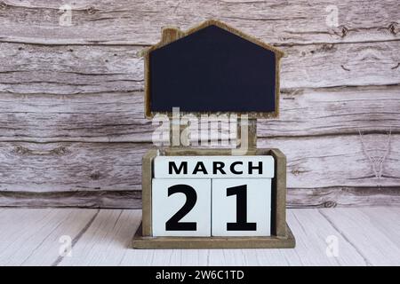 Tableau noir avec la date du calendrier de mars 21 sur le bloc de cube blanc sur la table en bois. Banque D'Images