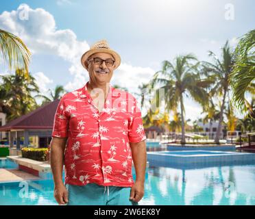 Touriste masculin mature souriant à la caméra en face d'une piscine extérieure Banque D'Images