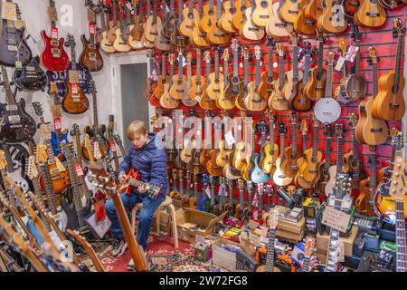 Magasin de guitare avec garçon jouant de la guitare Banque D'Images