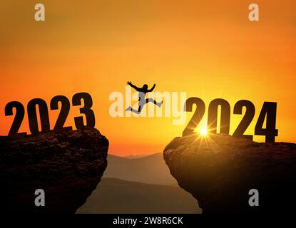 Homme sautant sur Cliff 2024 au-dessus du précipice à Amazing Sunset. Concept du nouvel an. Symbole de départ et de bienvenue bonne année 2024. Les gens entrent Banque D'Images