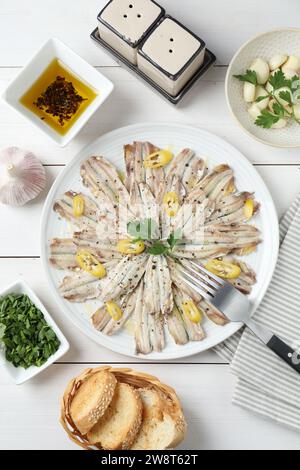 Anchois marinés savoureux servis sur une table en bois blanc, à plat Banque D'Images