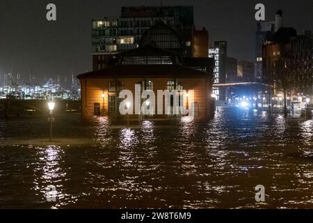 Hambourg, Allemagne. 22 décembre 2023. L'eau de l'Elbe est poussée sur le marché aux poissons lors d'une onde de tempête. L'Agence fédérale maritime et hydrographique a prédit une onde de tempête sévère à Hambourg pendant la nuit en raison de la dépression de tempête 'Zoltant'. Crédit : Bodo Marks/dpa/Alamy Live News Banque D'Images