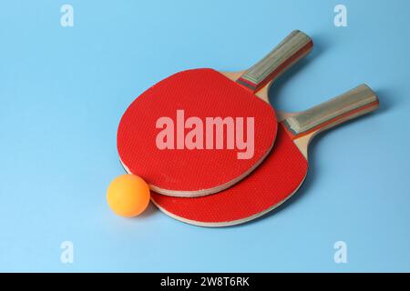 Balle de ping-pong et raquettes sur fond bleu clair Banque D'Images