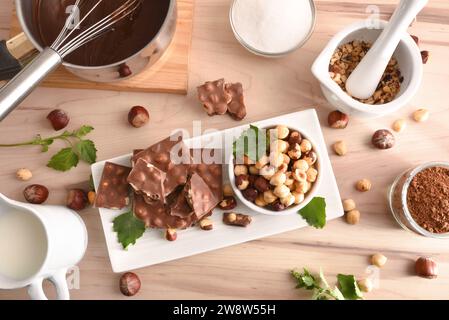 faire du chocolat avec des noisettes avec des ingrédients sur un banc de cuisine en bois et des outils. Vue de dessus. Banque D'Images