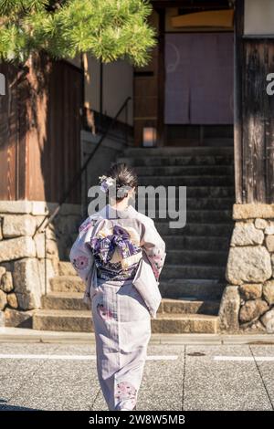 Japonais kimono Portrait photographie de vue arrière. Kyoto, Japon. Arrière-plan des bâtiments traditionnels japonais Banque D'Images