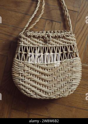 Vertical droit d'en haut image en gros plan d'un sac à bandoulière en paille sur parquet. Banque D'Images Vertical droit d'en haut image en gros plan d'un sac à bandoulière en paille sur parquet. Banque D'Images