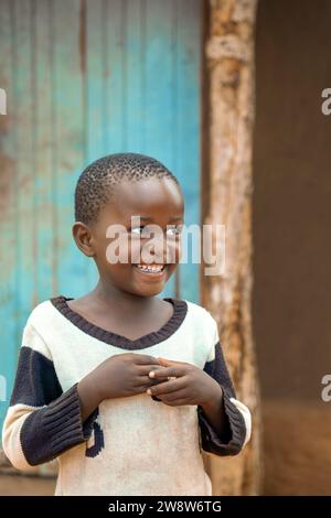 enfant africain dans le village debout dans la cour devant la maison Banque D'Images