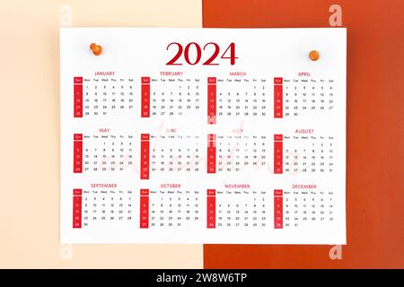 page de calendrier de 12 mois pour 2024 ans et épingles en bois sur fond rouge. Banque D'Images