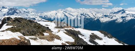 Une vue panoramique à couper le souffle attend les randonneurs sur le sentier du mur de neige au sommet du mont Whistler, avec les Rocheuses canadiennes qui s'étendent au loin. Banque D'Images