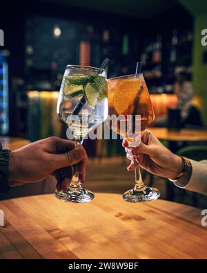 Deux mains avec des verres d'Aperol spritz et cocktail gin tonic Banque D'Images