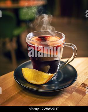 Vin chaud avec de l'orange dans des verres. Concept d'une boisson chaude traditionnelle d'hiver avec des épices et des fruits pour les vacances. Banque D'Images