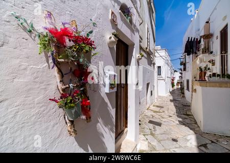 Maisons blanches dans les rues étroites de la petite ville de Mottola, décorées de fleurs colorées. Banque D'Images