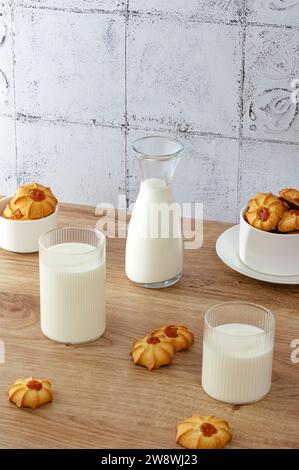 lait dans un verre et une carafe, biscuits éparpillés sur la table Banque D'Images