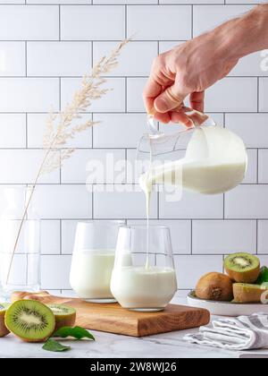 la main d'un homme verse du yaourt aux fruits maison d'une carafe dans un gl Banque D'Images