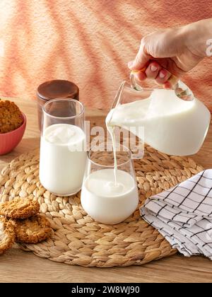 la main d'une femme verse du lait dans un verre Banque D'Images