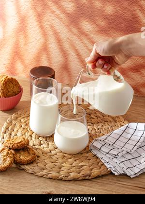 la main d'une femme verse du lait dans un verre Banque D'Images