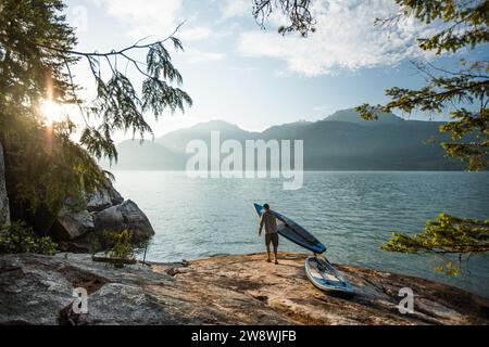 Sup paddle boarder se prépare pour une pagaie tôt le matin. Banque D'Images