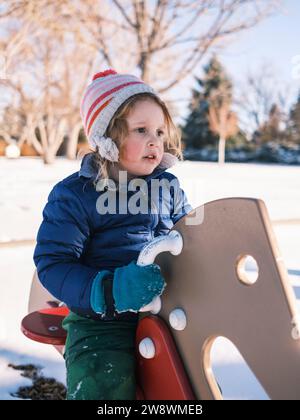 Enfant portant des vêtements chauds d'hiver jouant dans la neige Banque D'Images