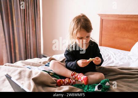 Une fille assise sur un lit dans une chambre Banque D'Images